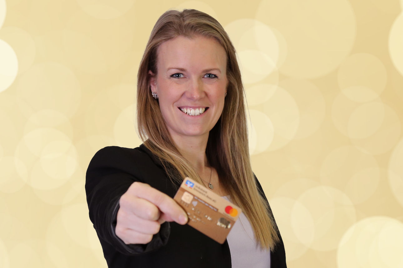 Lächelnde Frau hält goldene Kreditkarte in die Kamera