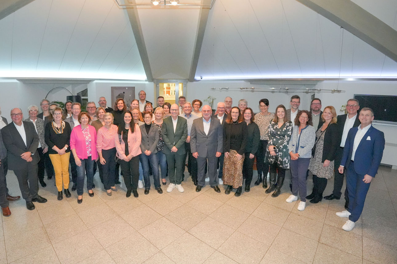 Eine größere Gruppe von verschiedenen Mitarbeiter:innen lächelt gemeinsam in die Kamera.