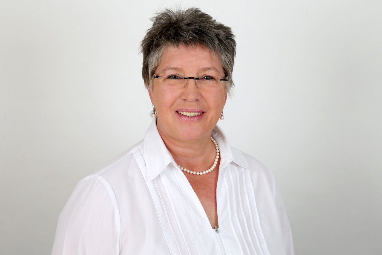 Eine lächelnder Frau schaut in die Kamera.