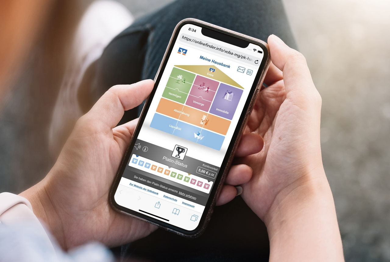 Mann hält Smartphone in Händen, auf dem das Hausbank-Programm der Volksbank angezeigt wird