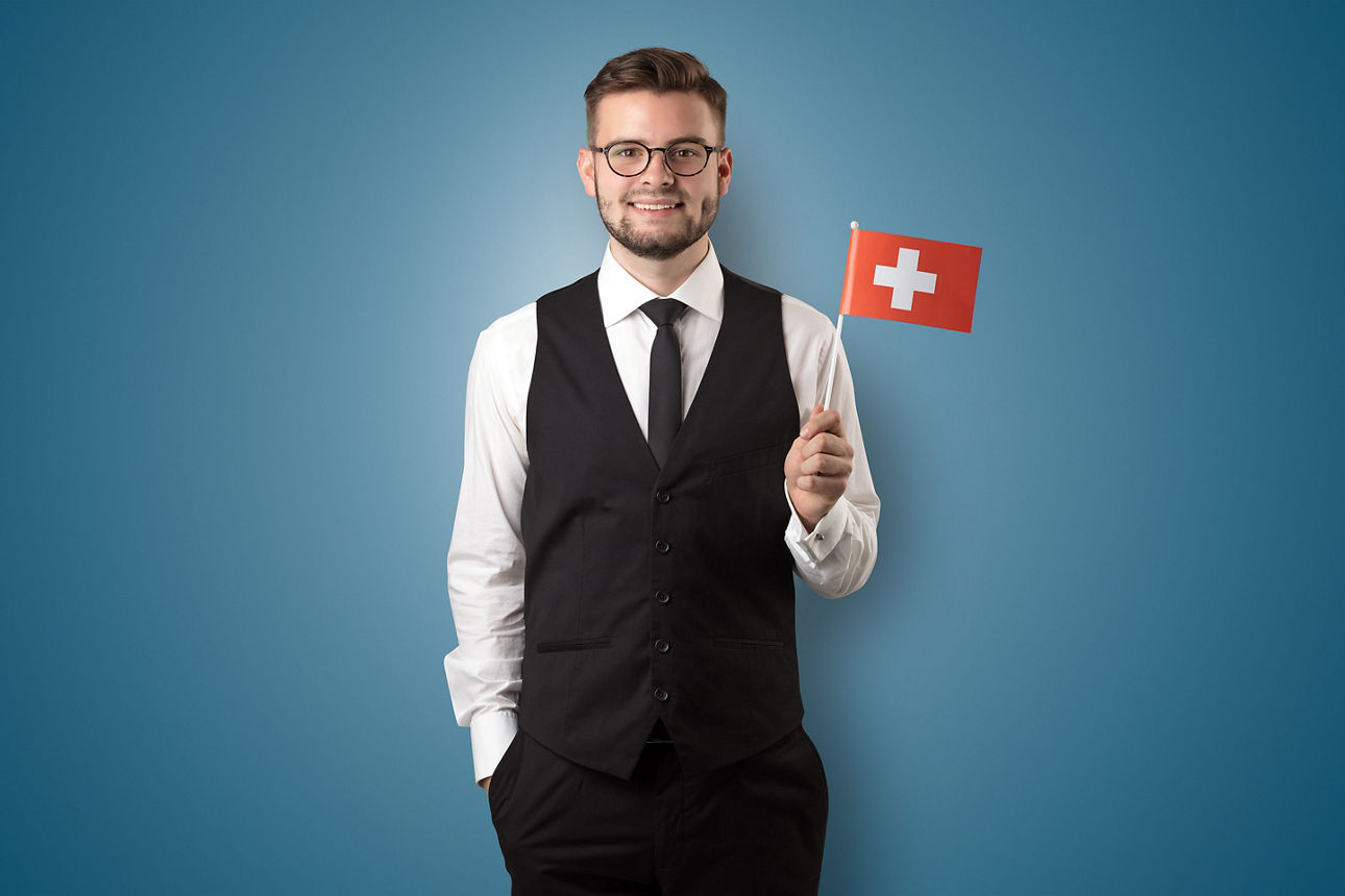 Bild eines Mannes, der eine kleine Flagge der Schweiz in der Hand hält.
