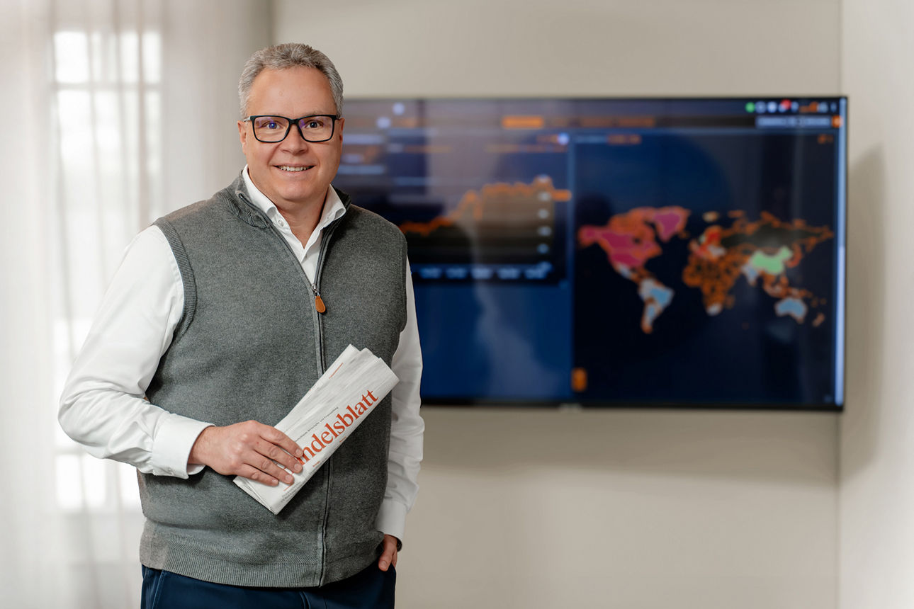 Ein Mann steht vor einem Fernseher und lächelt