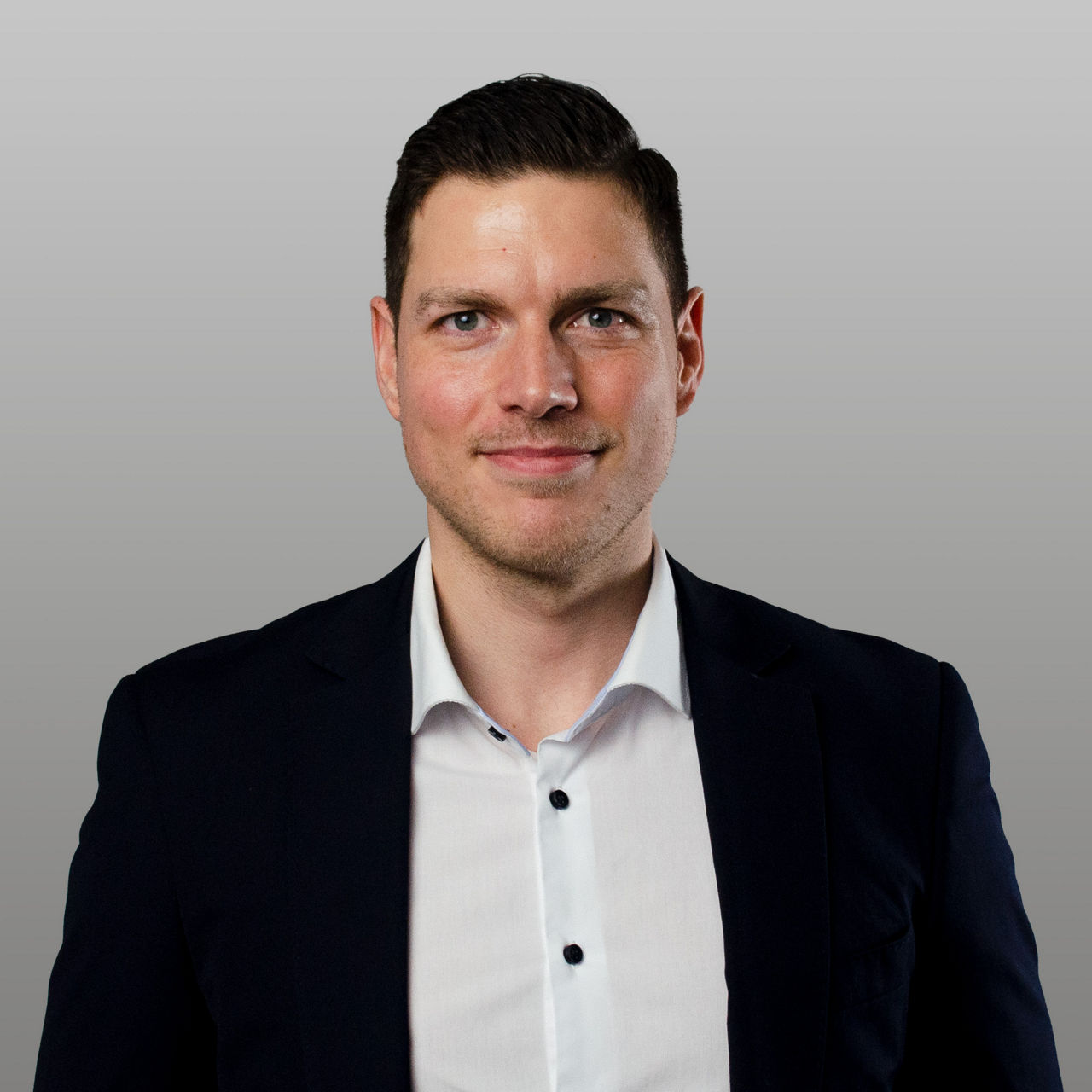 Firmenkundenberater Tobias Grieger vor grauem Hintergrund