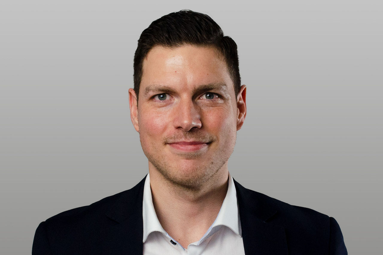 Firmenkundenberater Tobias Grieger vor grauem Hintergrund