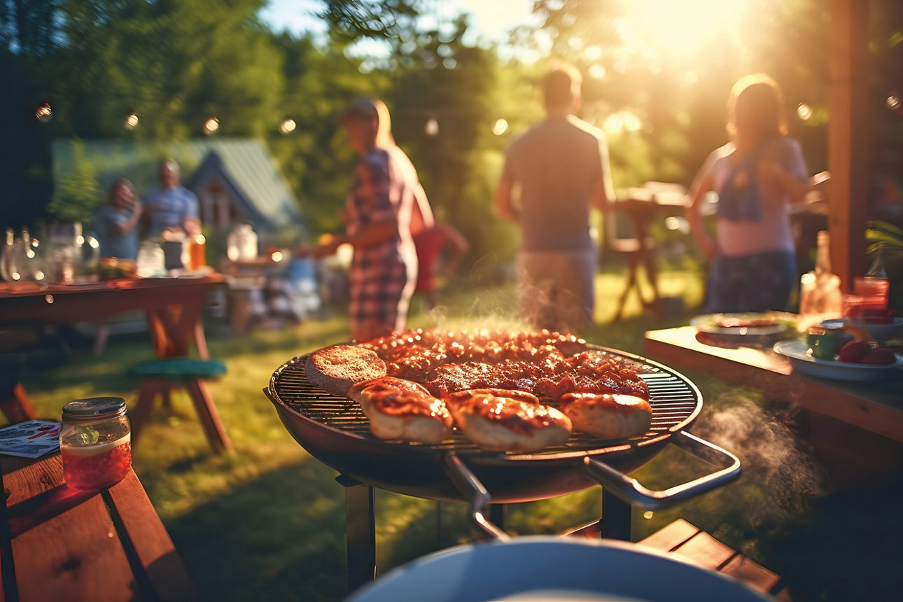 Menschen stehen im Garten bei einer Grillparty
