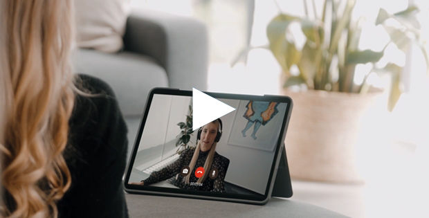 Blonde Frau schaut im Wohnzimmer auf den Laptopbildschirm und spricht per Video mit einer Beraterin.