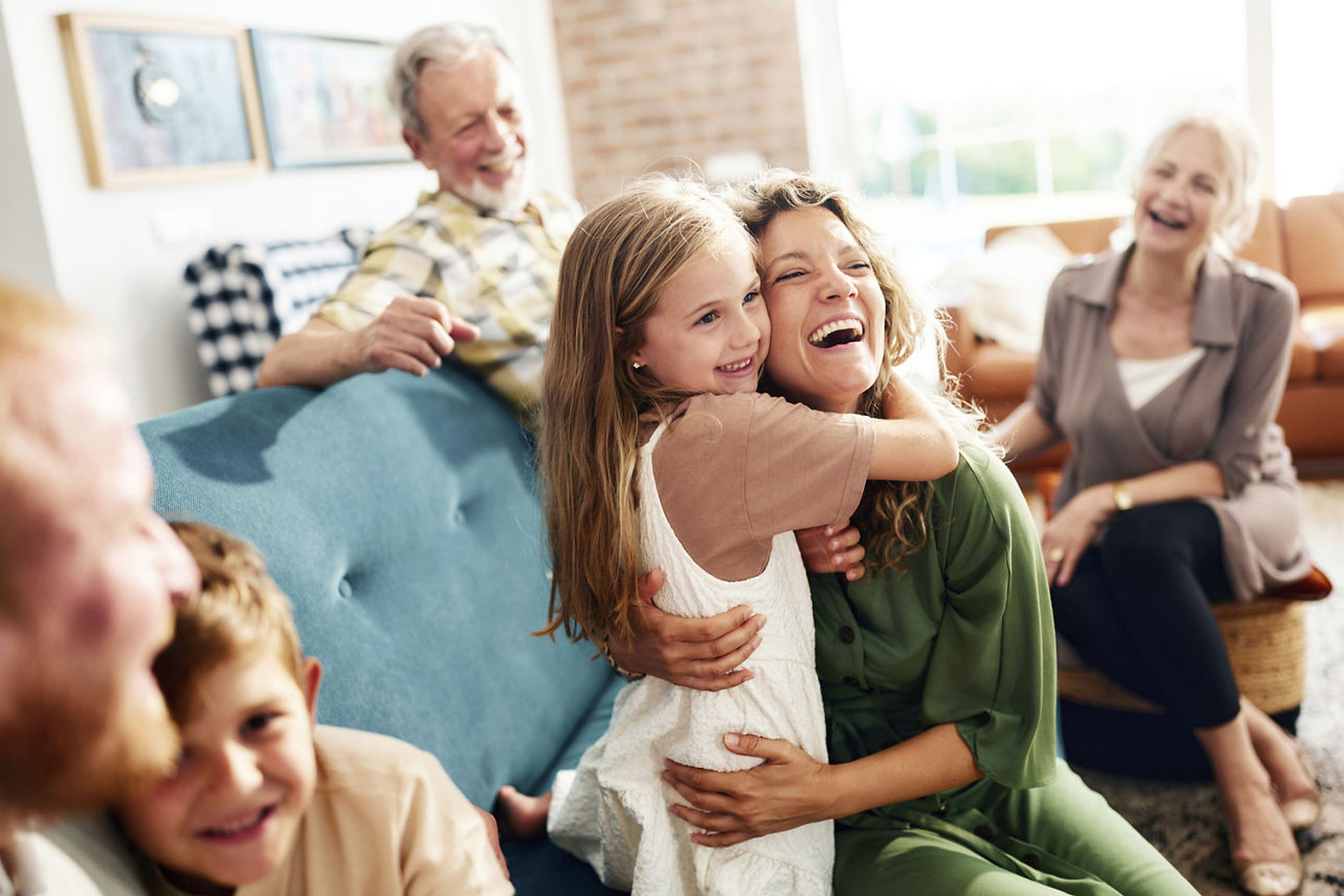 Großfamilie im Wohnzimmer, glückliche Mutter und ihre Tochter umarmen sich