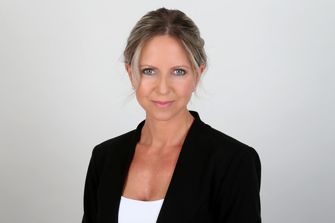 Eine lächelnde Frau schaut in die Kamera.