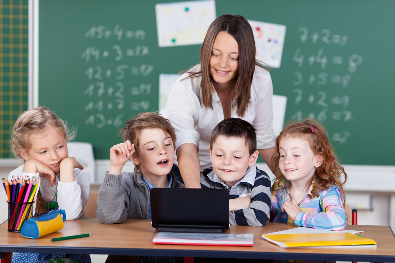 Lehrerin zeigt Schülern etwas am Laptop