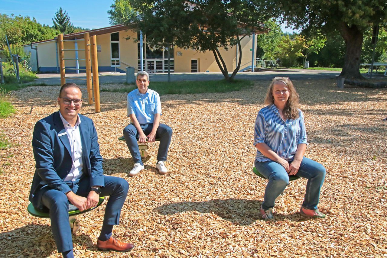 Mitarbeiter der VR-Bank und Lehrer der Grundschule auf den neuen Spielgeräten