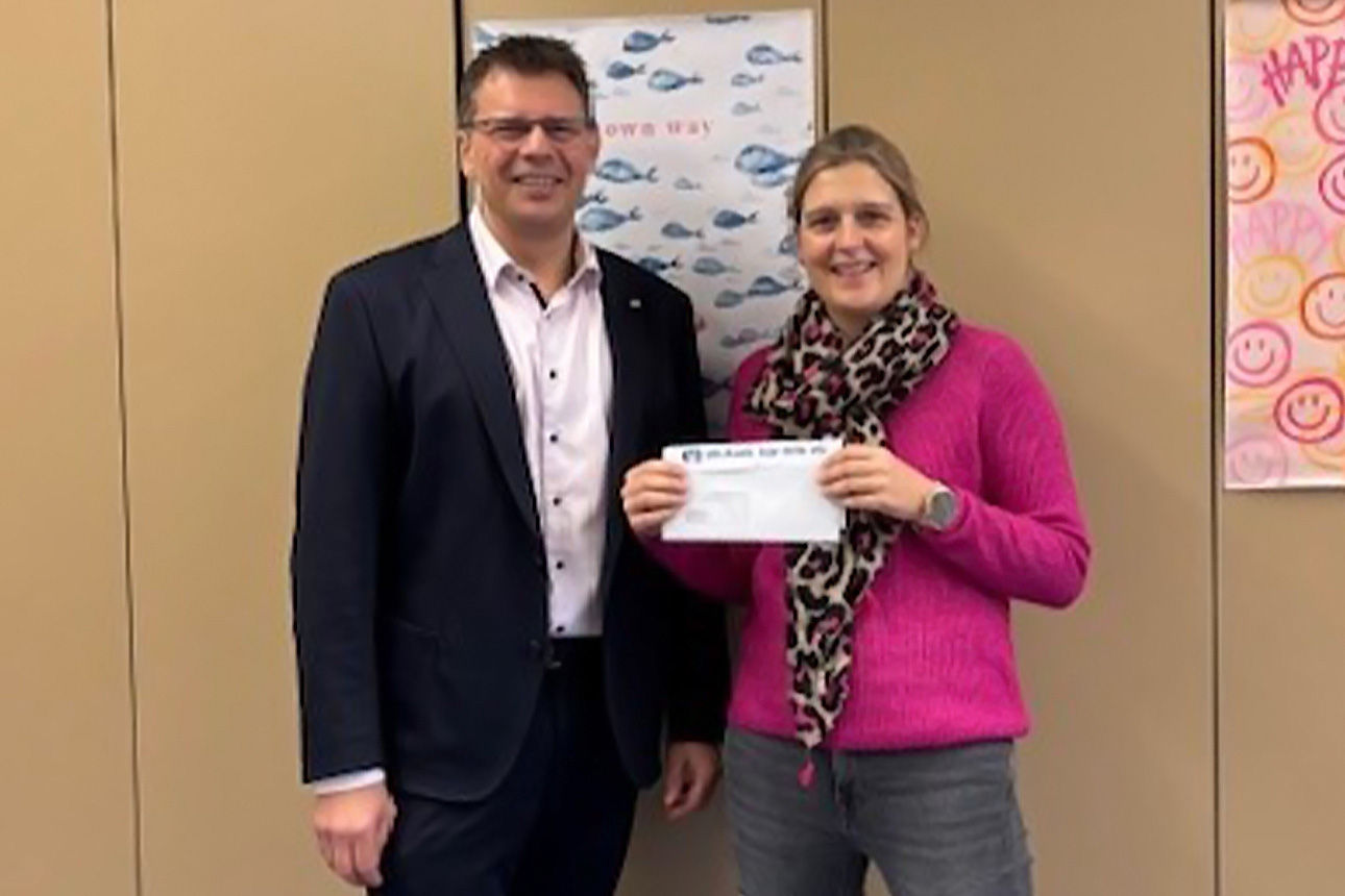 Ein Mann und eine Frau lächeln in die Kamera. Sie halten einen Briefumschlag in der Hand.