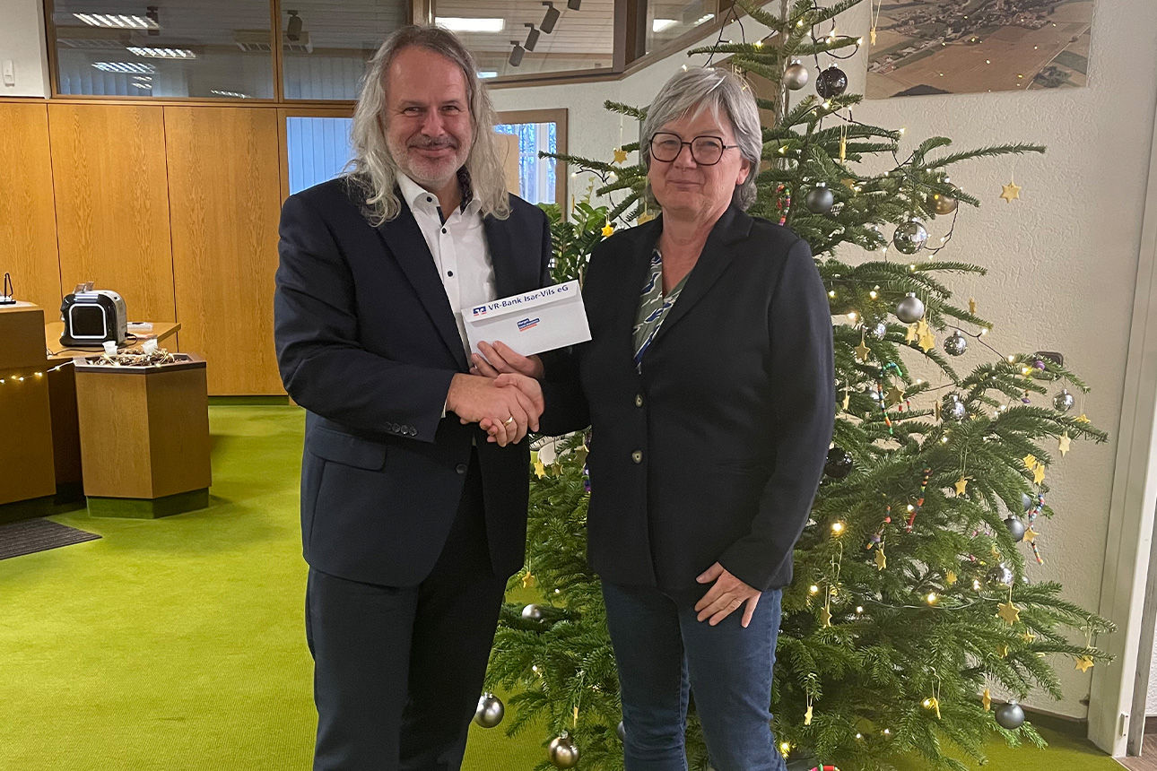 Ein Mann und eine Frau lächeln in die Kamera. Sie halten einen Briefumschlag in der Hand.