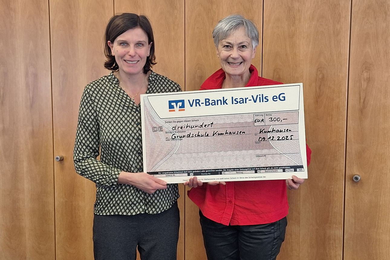 Zwei Frauen lächeln in die Kamera und halten dabei einen Spendenscheck in der Hand. 