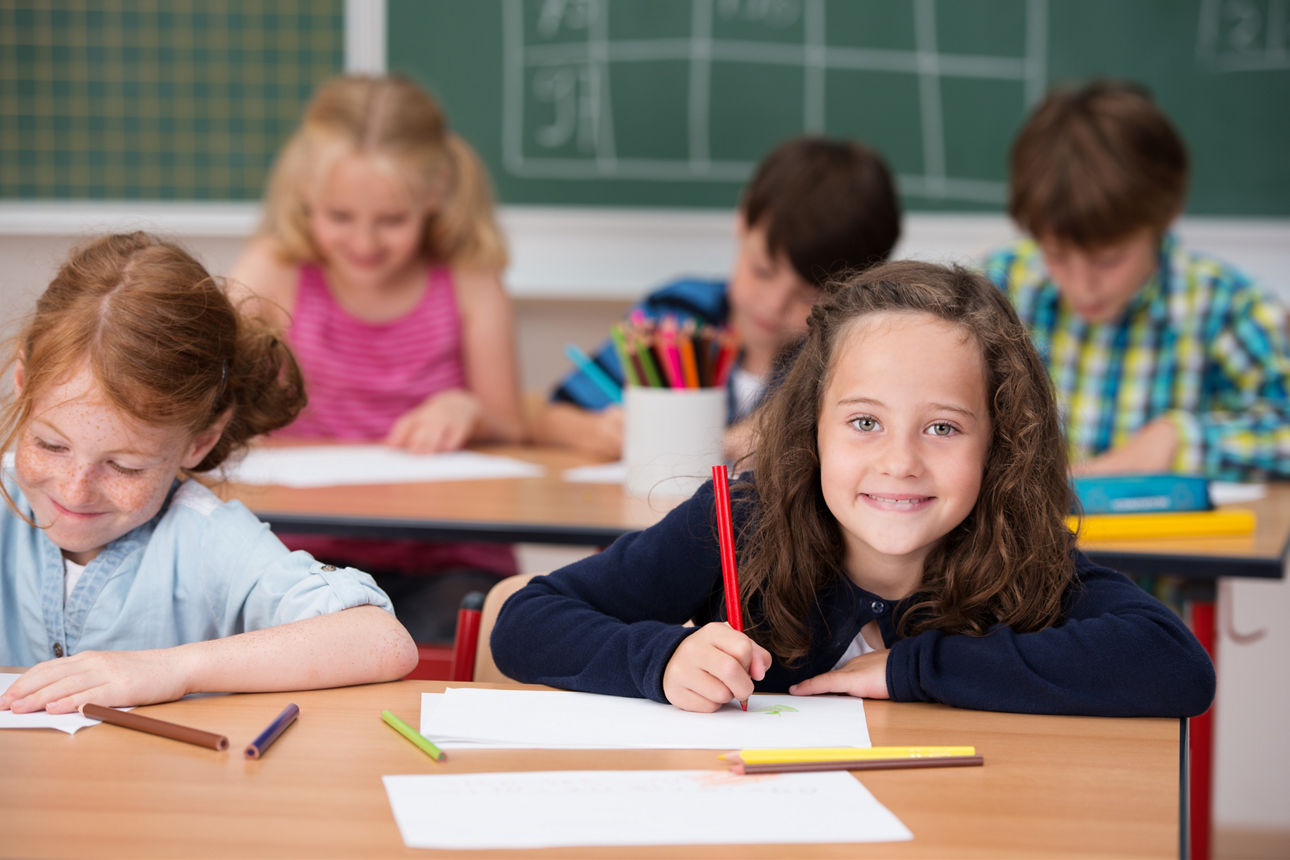 Kinder vor einer Tafel mit Daumen nach oben lachend