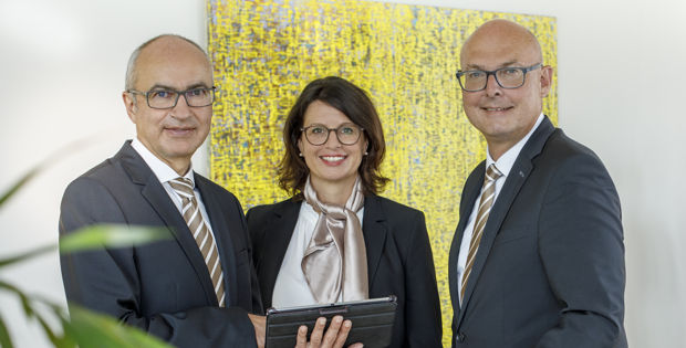 Zwei Männer und zwei Frauen stehen lächelnd nebeneinander