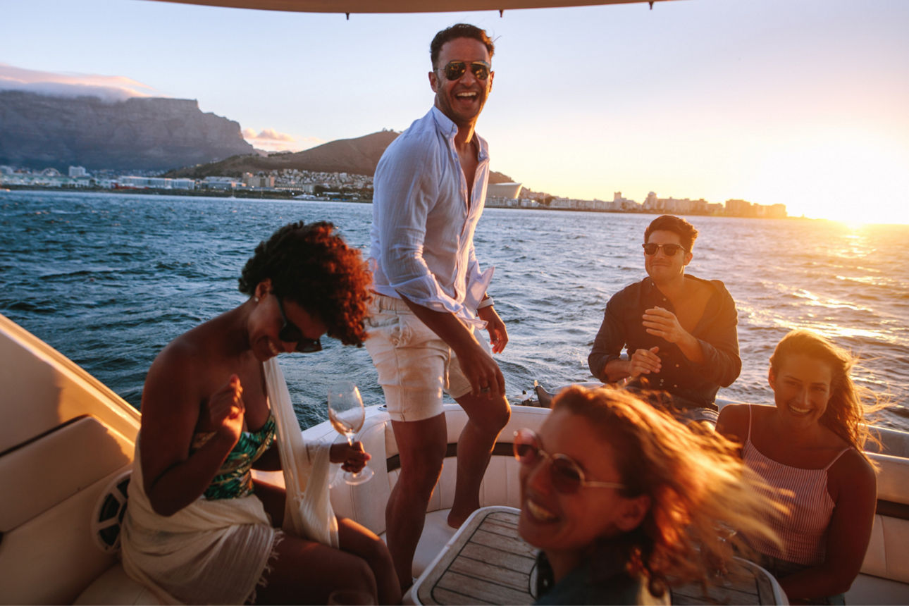 Gruppe junger Menschen auf einem Boot bei Sonnenuntergang