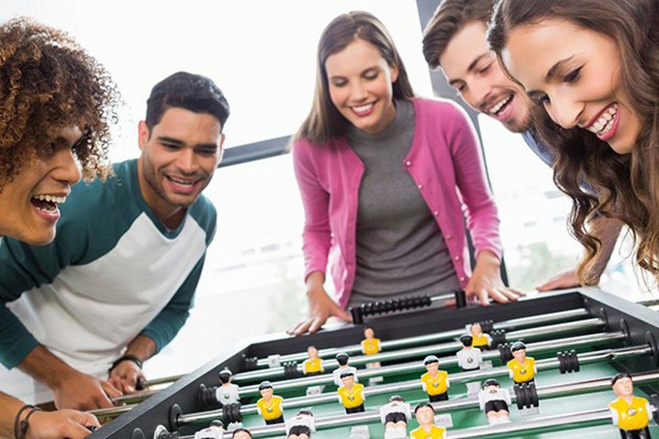 Gruppe von Freunden spielt zusammen Tischkicker