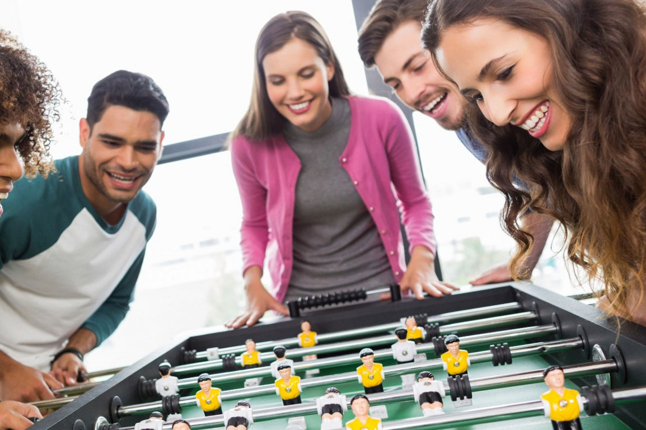 Junge Menschen spielen gemeinsam Tischkicker