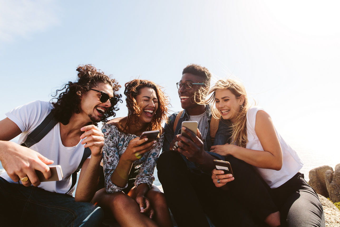 Vier Personen nutzen Smartphones im Freien, Hinweis auf Mitgliedschaft für junge Menschen