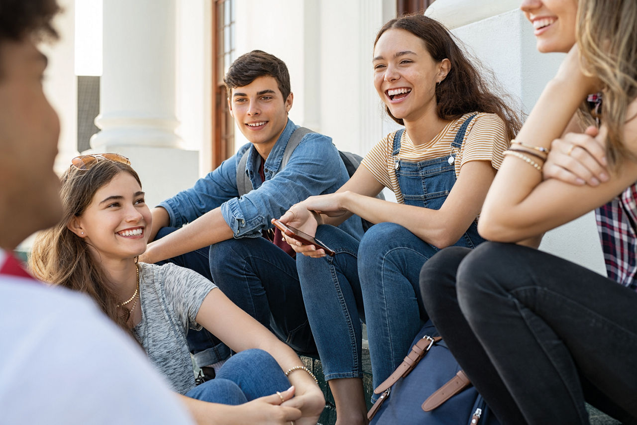 Fünf Jugendliche sitzen gemeinsam in einer Runde und lachen