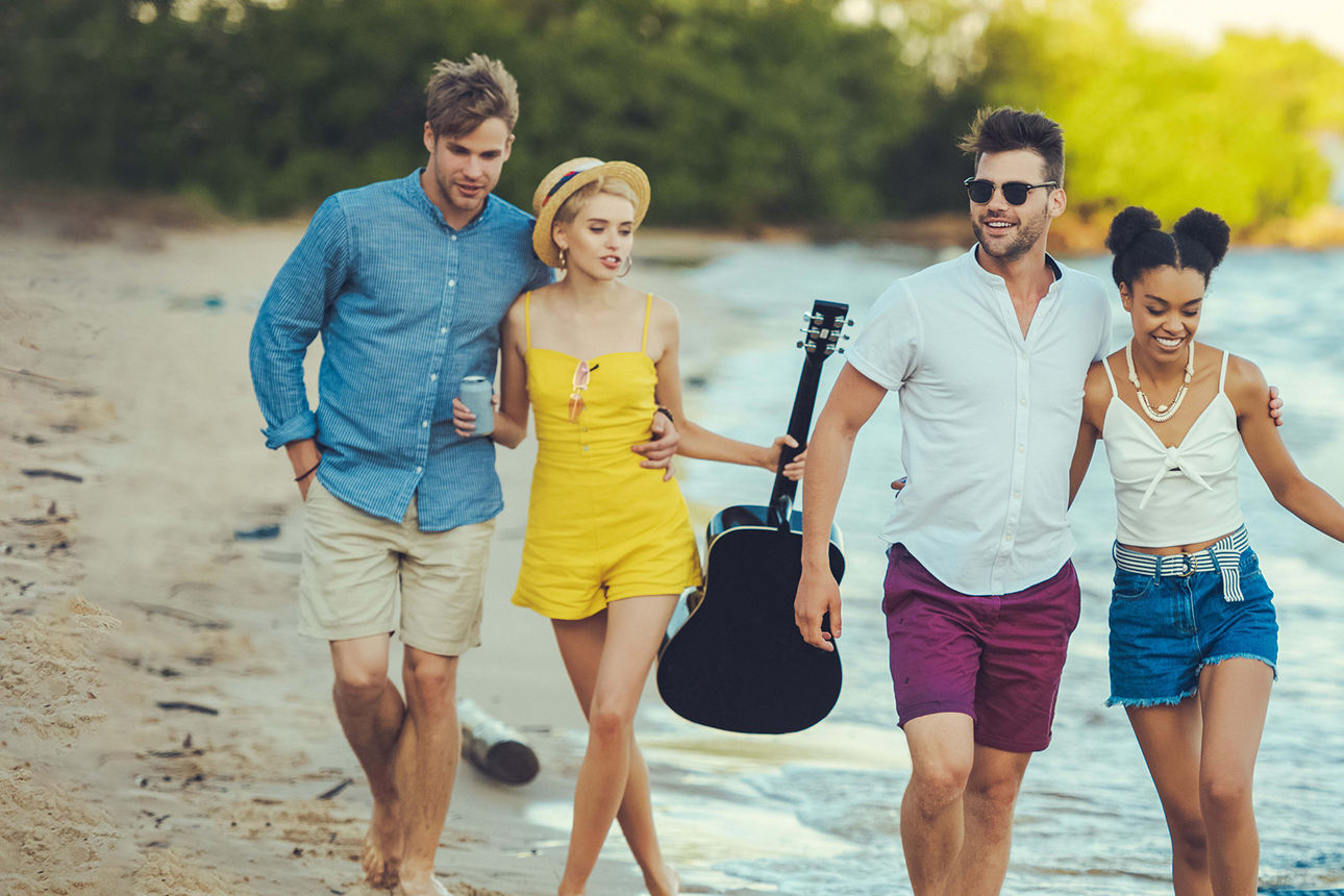 zwei Pärchen gehen Hände haltend über den Strand