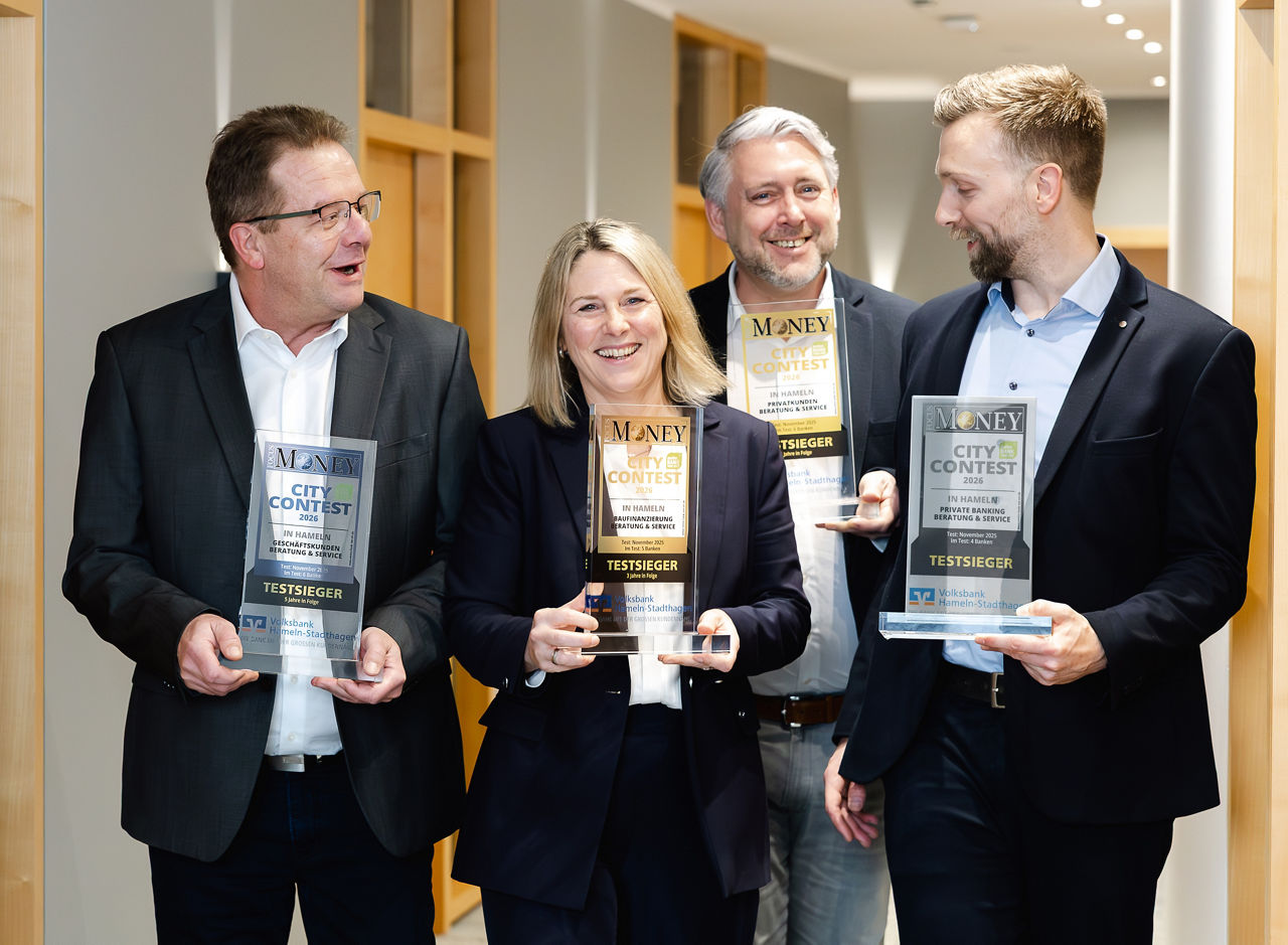 Vier Personen stehen in einem Flur und halten Auszeichnungen des FOCUS MONEY City Contest in den Händen.