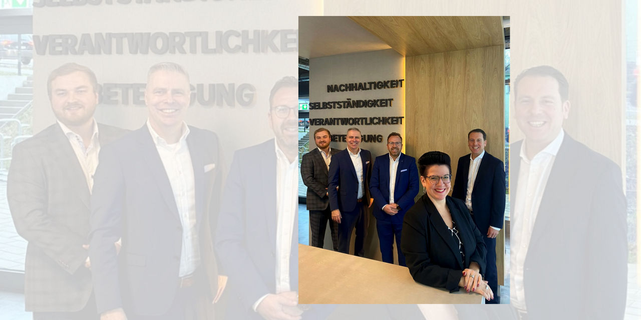 Das Team der gewerblichen Immobilienfinanzierung steht vor einer Wand mit Werten.