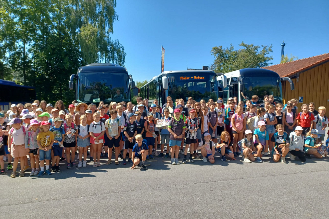 Kinder stehen vor Reisebussen