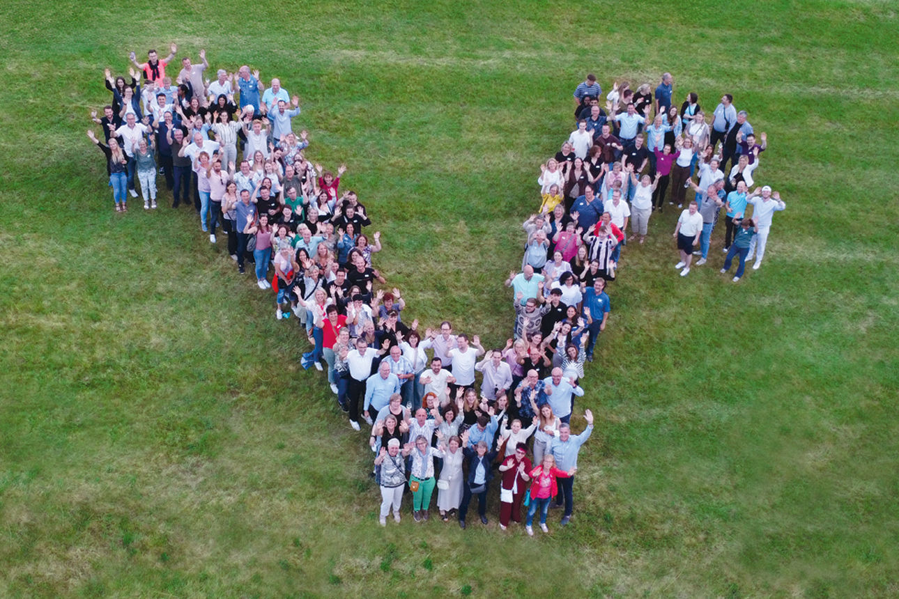 Lachende Gruppe von Mitarbeitenden in blauen Trikots der Volksbank beim Firmenlauf Bad Kreuznach