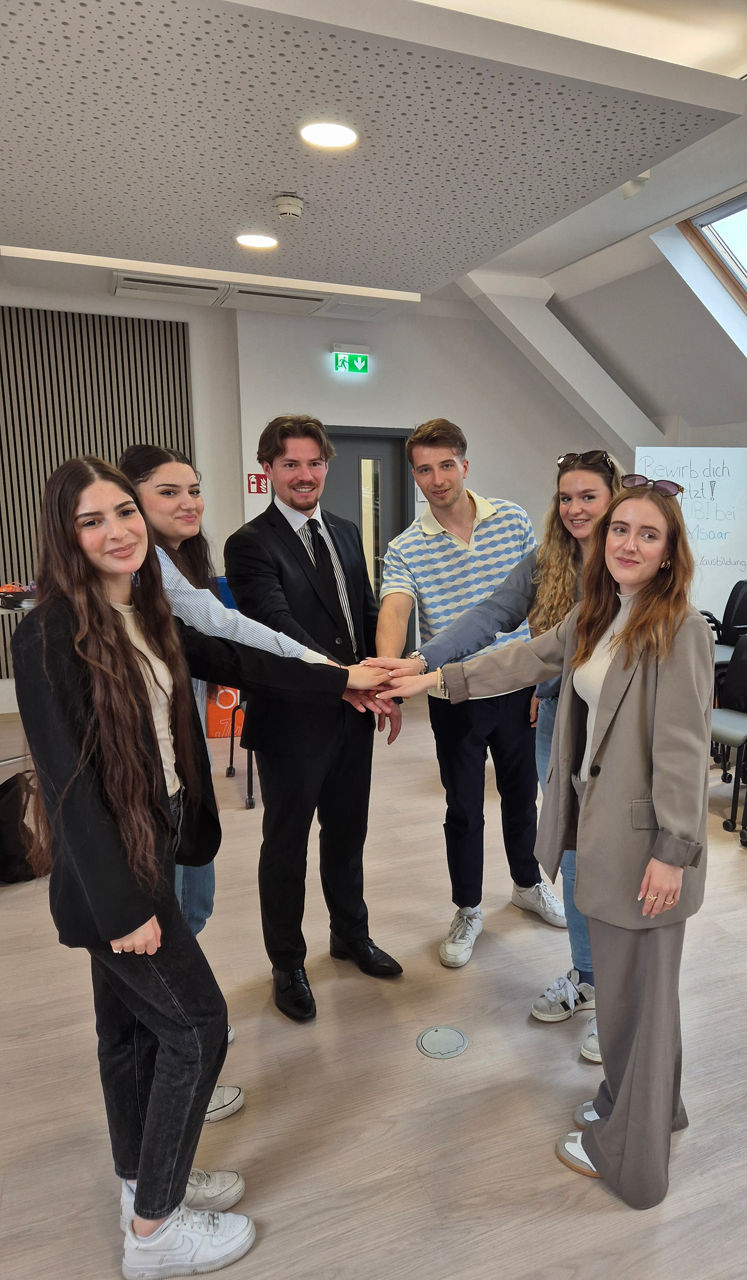 Die Azubis der Bank 1 Saar beim Drehtag, klatschen sich im Team ab