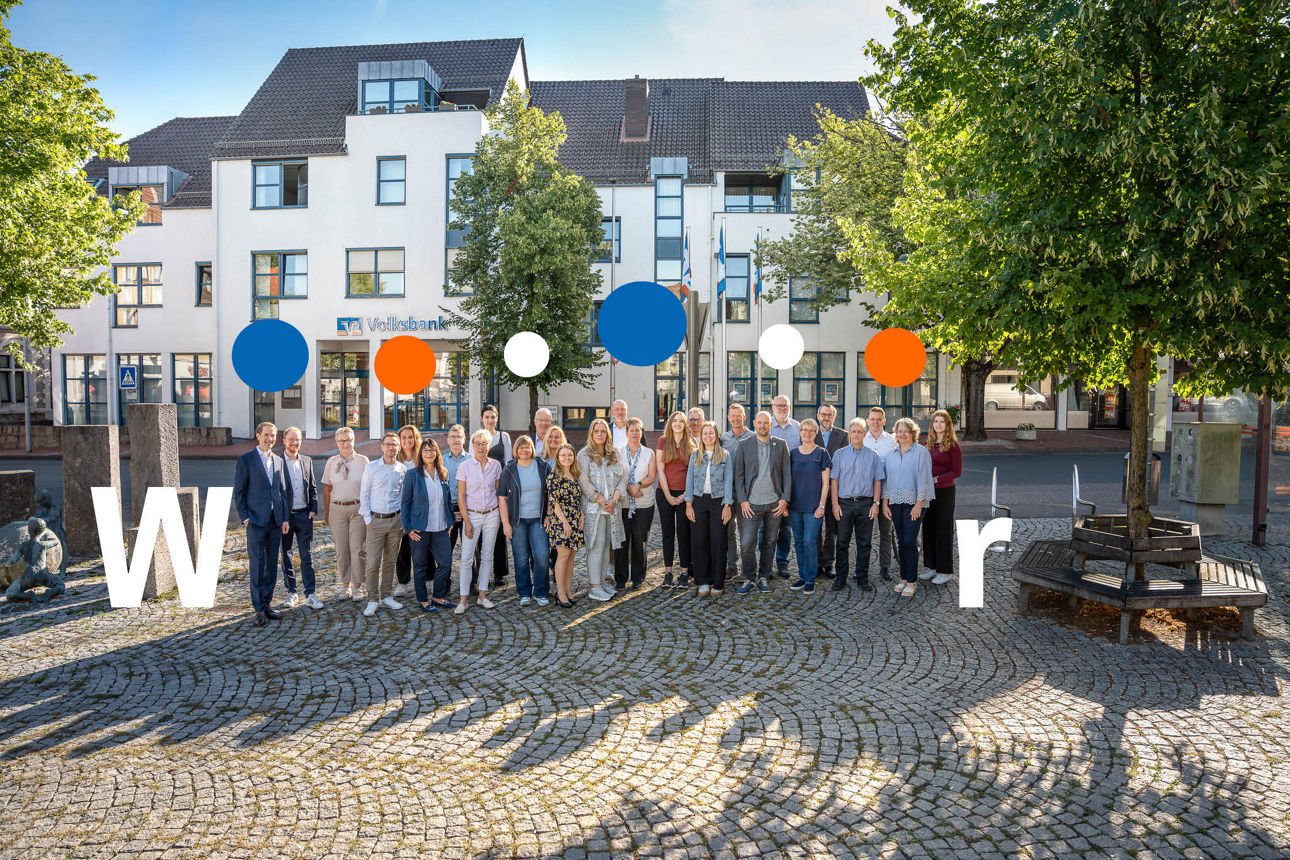 Eine Gruppe Mitarbeitender der Volksbank Bad Salzuflen auf dem Marktplatz in Schötmar vor dem Hauptgebaude der Volksbank