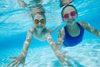 Zwei Mädchen mit Taucherbrille schwimmen unter Wasser