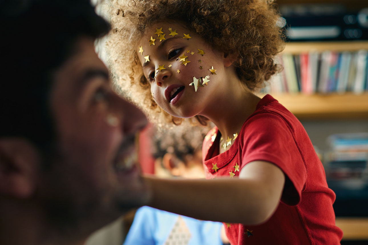 Kind mit lockigem Haar und Sternen im Gesicht, das interessiert etwas betrachtet, mit einer Bibliothek im Hintergrund