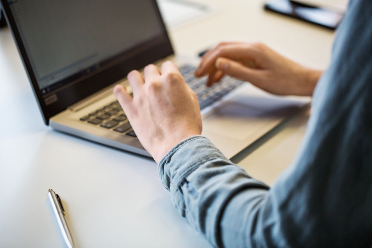Hände von Frau am Laptop im Büro