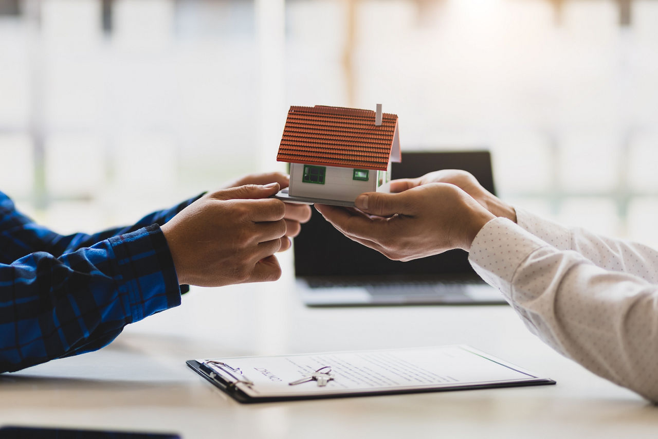Zwei Personen halten ein kleines Miniaturhaus in den Händen