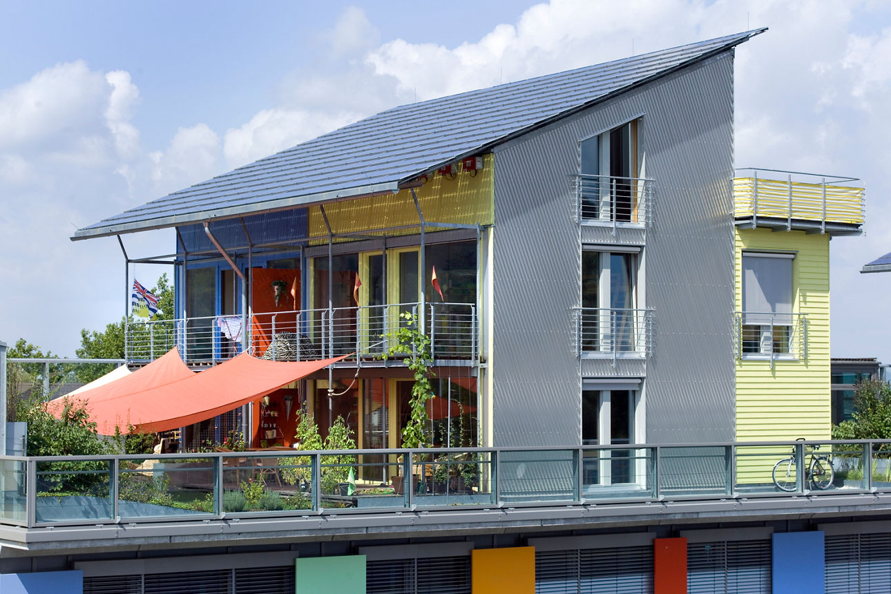 Ein modernes Wohngebäude mit bunter Fassade, Solarpanels auf dem Dach und großzügigem Balkonbereich.