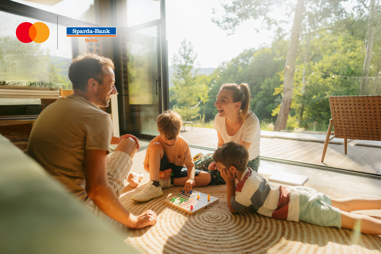 Familie sitzt im Wohnzimmer zusammen auf dem Boden
