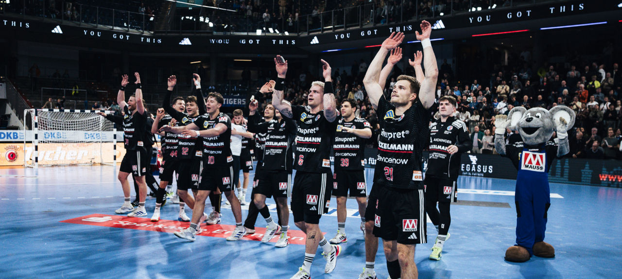 Eine Handballmannschaft hebt die Hände hoch.