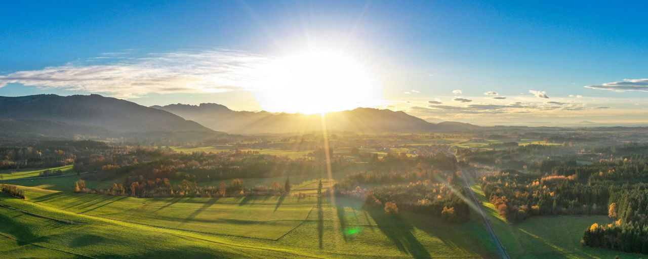 Landschaftsbild vom Allgäu mit Bergen und Sonnenstrahlen im Hintergrund