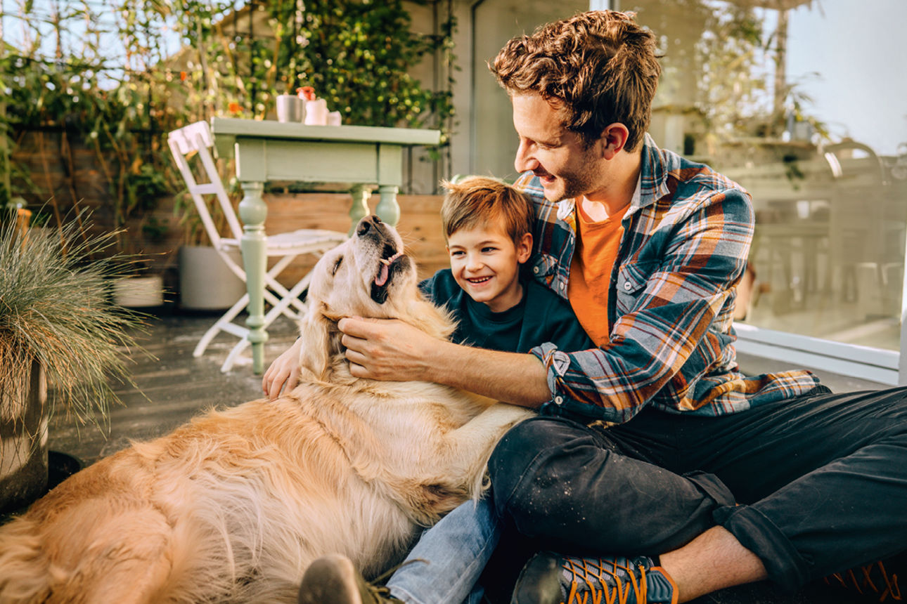 Lachendes Kind steht zwischen zwei Personen, die Händchen halten