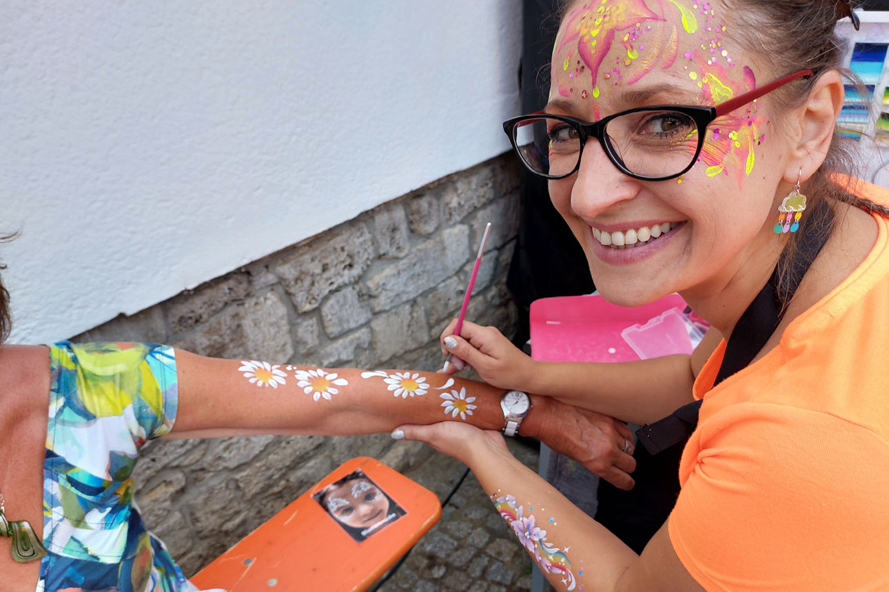 Janin Gutzmann von "Pinselgelgedöns" malt Margeriten auf den Arm eines Gastes