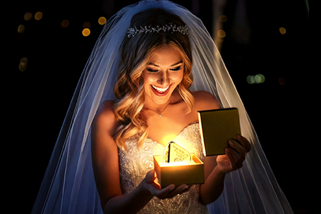 Liebes Gold - Frau mit offener Goldschachtel in einem Hochzeitskleid