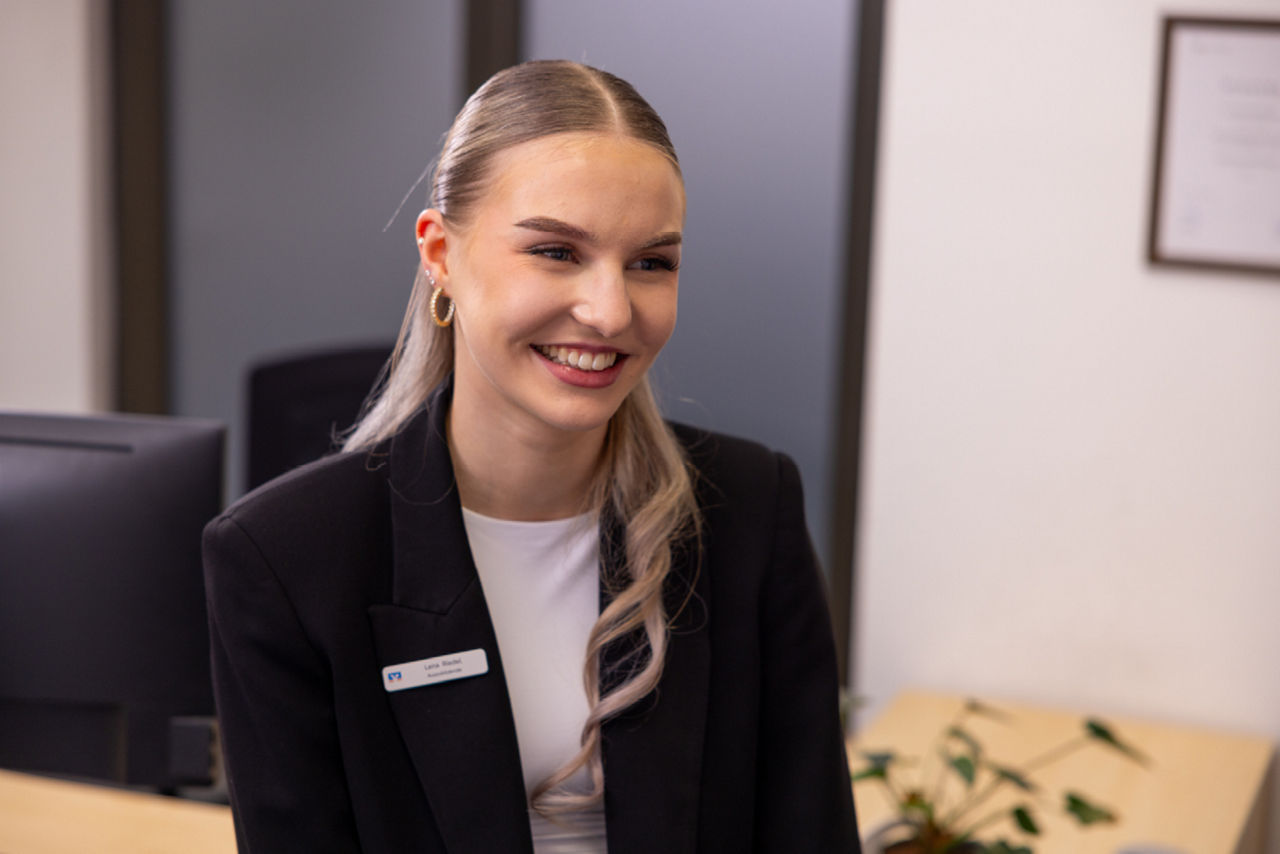 junge Frau sitzt lächelnd am Schreibtisch