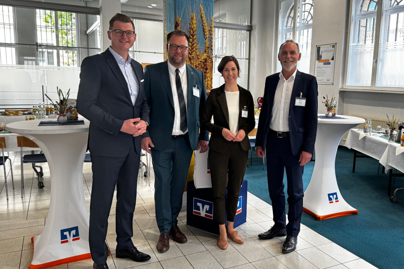 Vorstände der VR Bank und die Gäste stehen im Veranstaltungsraum