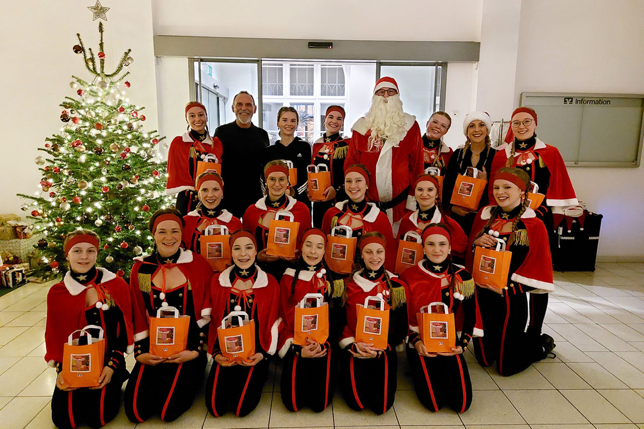 Gruppe von Mädchen und jungen Frauen im weihnachtlichen Kostüm vor einem Tannenbaum