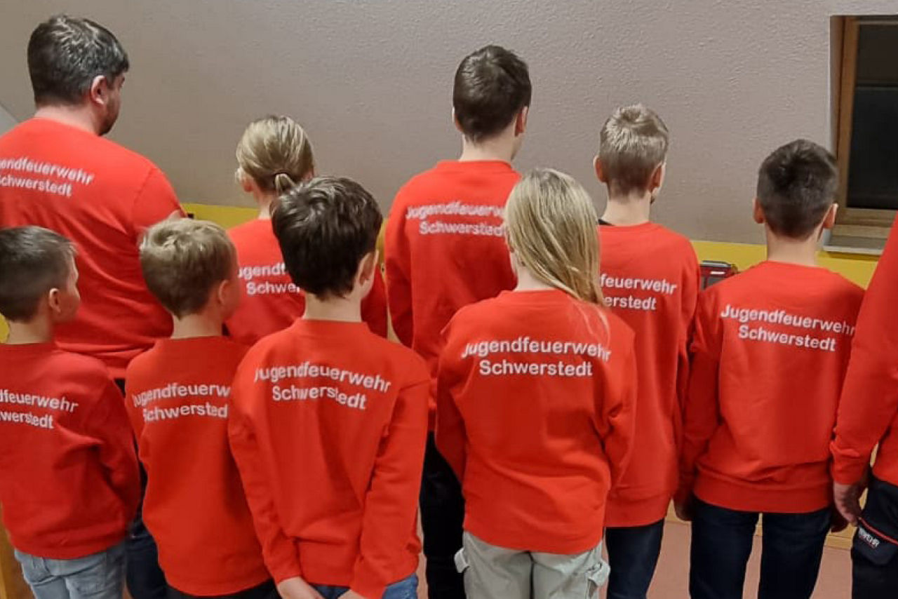 stehende Kinder mit Feuerwehrpullis von hinten fotografiert
