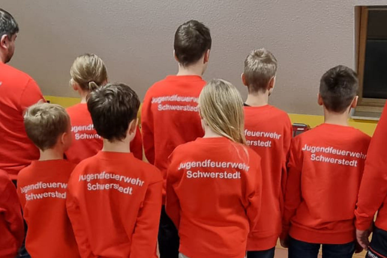 stehende Kinder mit Feuerwehrpullis von hinten fotografiert