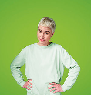 Frau mit grünem Pulli und den Armen in der Hüfte 