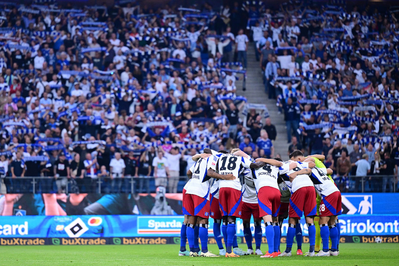 Im Hintergrund der Tribüne steht das HSV-Team auf Spielefld