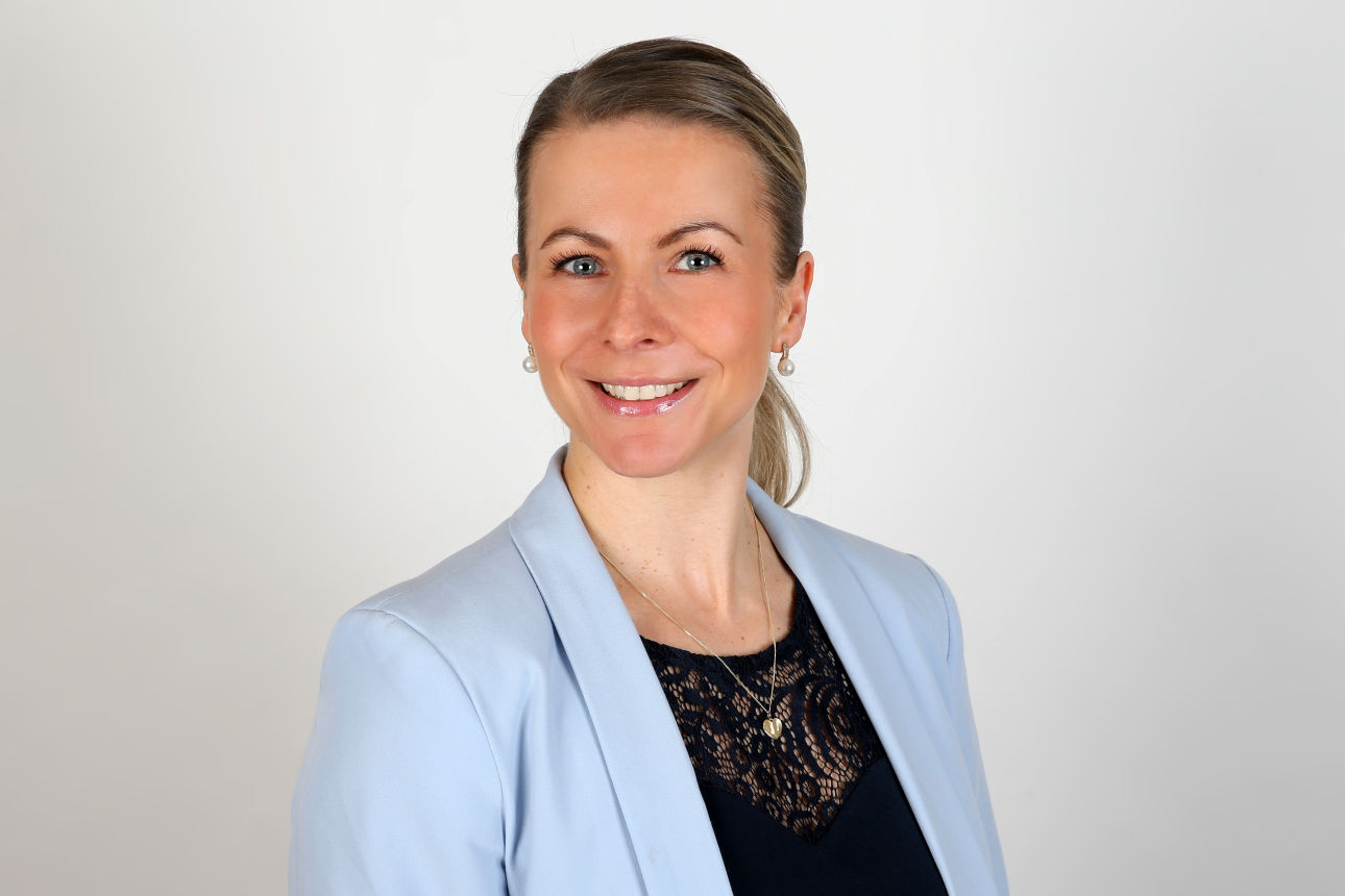 Ein lächelnder Frau schaut in die Kamera.